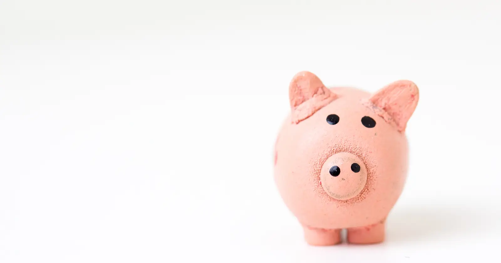 A small pink piggy bank standing on a plain white surface